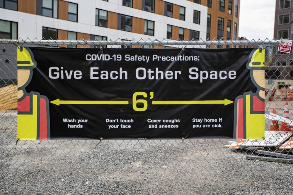 A COVID-19 safety precaution sign at a construction site in Central Sq in Cambridge. (Jesse Costa/WBUR)