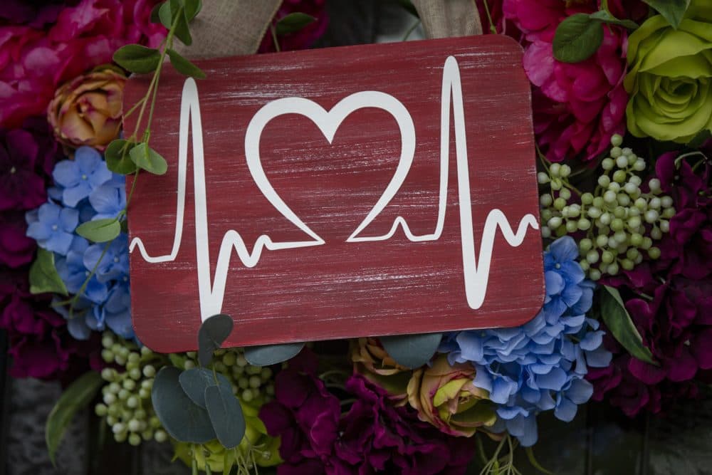 A sign, received anonymously in the mail, hangs in the center of a wreath on the front door of the Athienites home, indicating health care workers who have survived COVID. (Jesse Costa/WBUR)