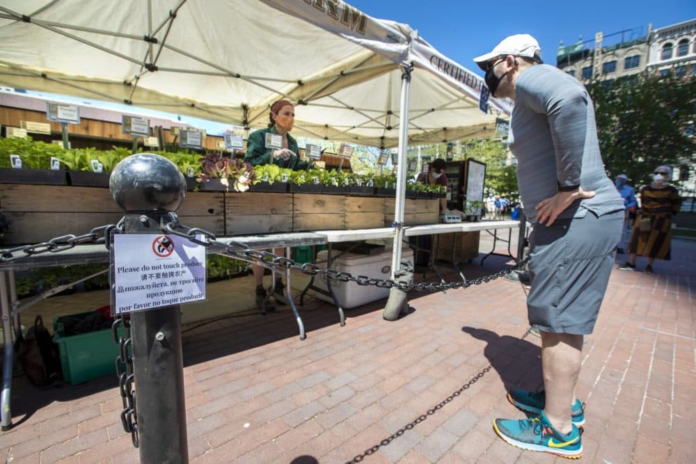A man puts in his order of produce and plants at the Atlas Farm statnd at the Copley Square Farmers Market. (Jesse Costa/WBUR)