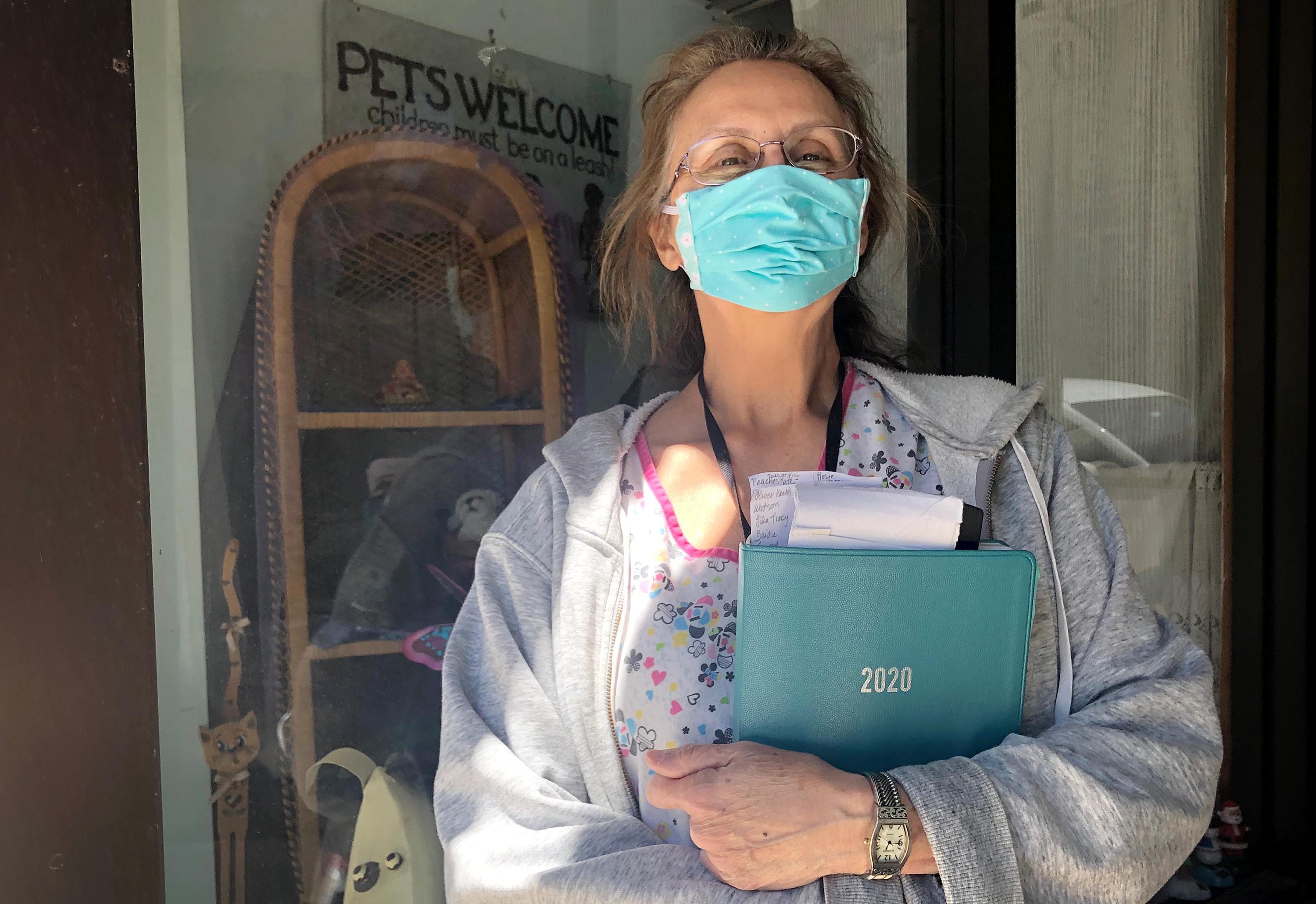Sandy Koot, the owner of Gentle Grooms, stands outside her business with her appointment book. She doesn’t take new customers, and many customers book a year in advance. (Bruce Gellerman/WBUR)