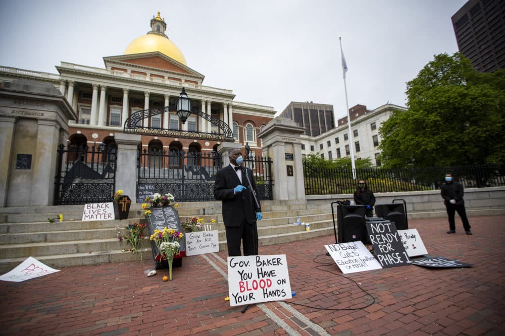 Lewis Elisa of the Boston Black COVID-19 coalition speaks in front of the State House during a protest to honor black people and Latinos who have died of COVID-19. (Jesse Costa/WBUR)