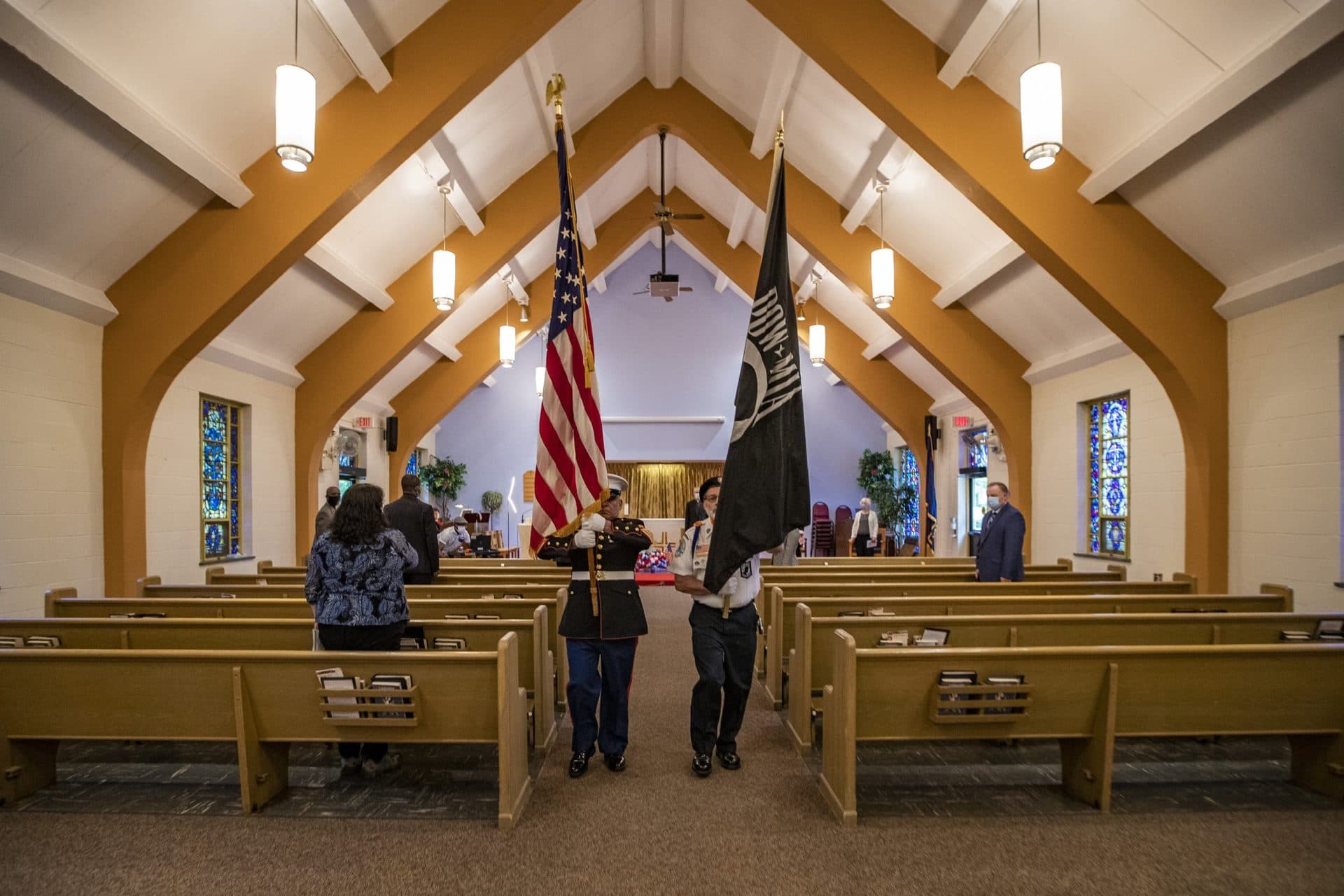 Thomas “Gunny” Estrada, left, and Jean Pinard perform the retirement of the colors to conclude the Memorial Day Interfaith Service at the Bedford VA Hospital chapel. (Jesse Costa/WBUR)