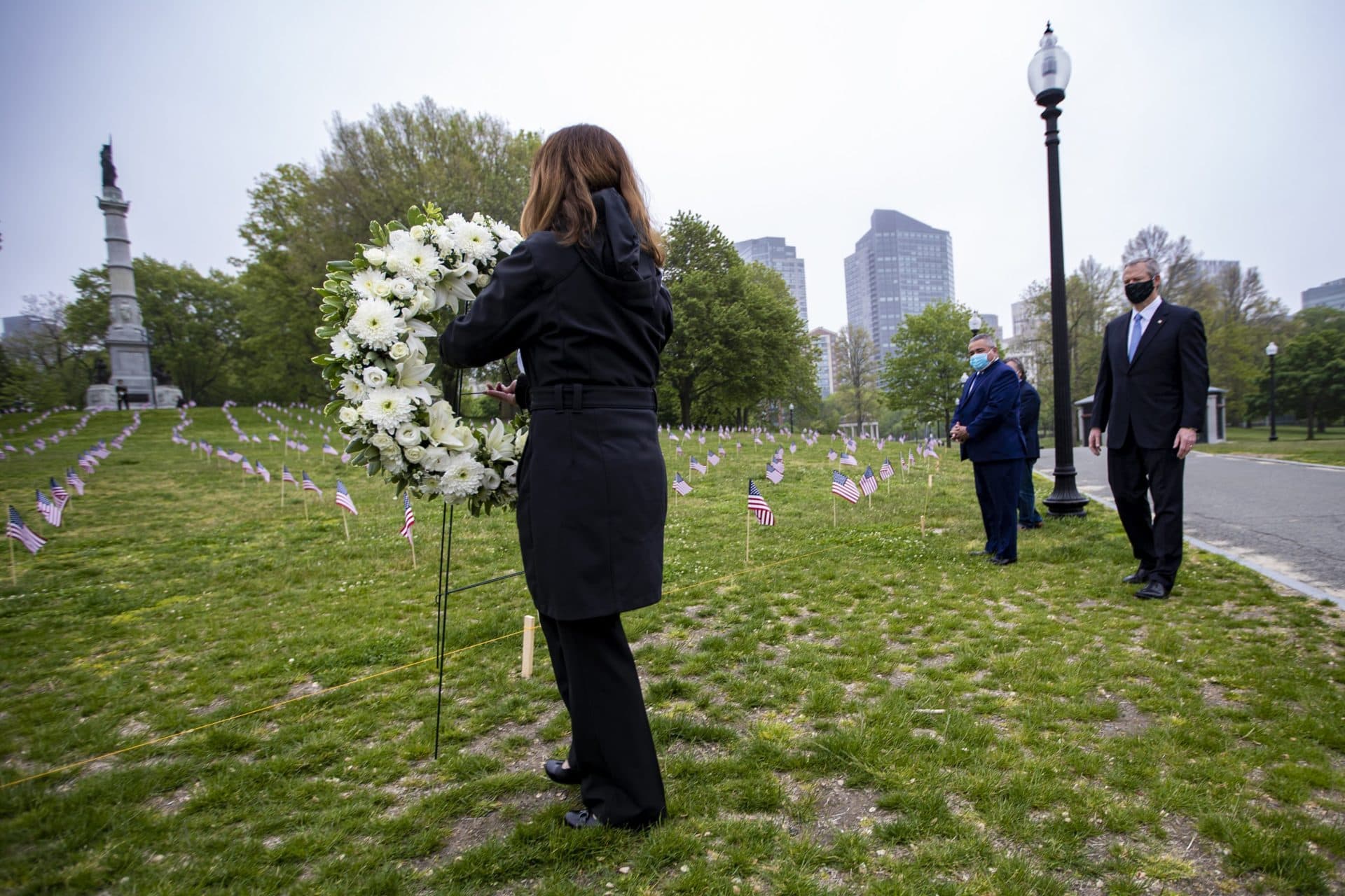 Baker watches as Diane Nealon, executive director of the Massachusetts Military Heroes Fund, places a wreath at the base of the hill where the Soldiers and Sailors Monument in the Boston Common is located. (Jesse Costa/WBUR)