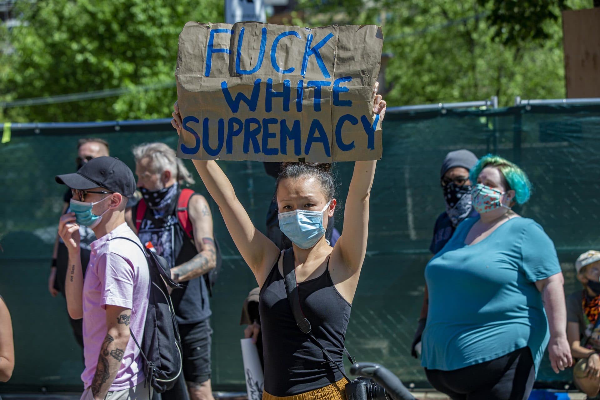 A counter-protester holds a sign during the Reopen Massachusetts NOW rally in front of the State House on Sunday morning. (Jesse Costa/WBUR)