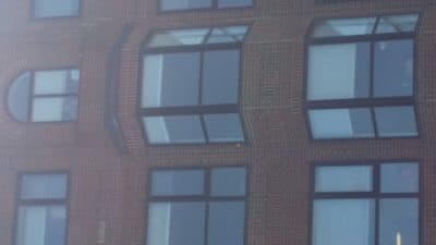 The author's mother, under quarantine, in the window of her residence in Somerville, Mass., in late April. She continues to do battle with COVID-19. (Cynthia Dockrell/ Courtesy)