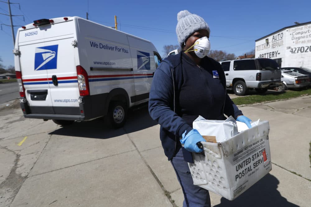 A United States Postal worker makes a delivery with gloves and a mask in Warren, Mich., Thursday, April 2, 2020.  (Paul Sancya/AP)