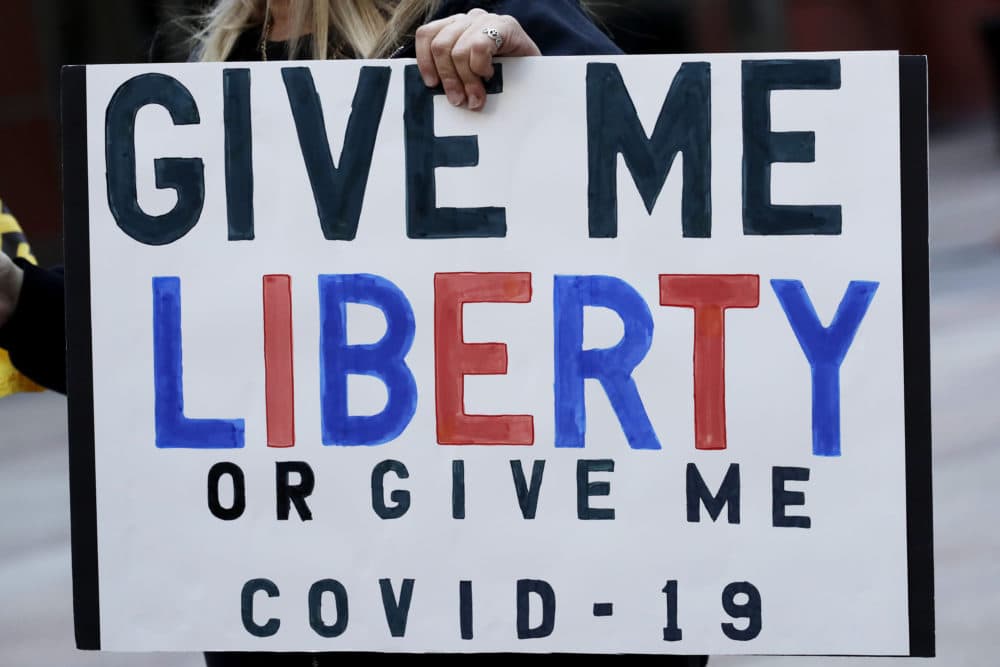 A protester holds a sign outside the Thompson Center in downtown Chicago, Friday, May 1, 2020. The Friday demonstration is the latest in a series of protests around the country against stay-at-home orders designed to slow the spread of the coronavirus. (Nam Y. Huh/AP)