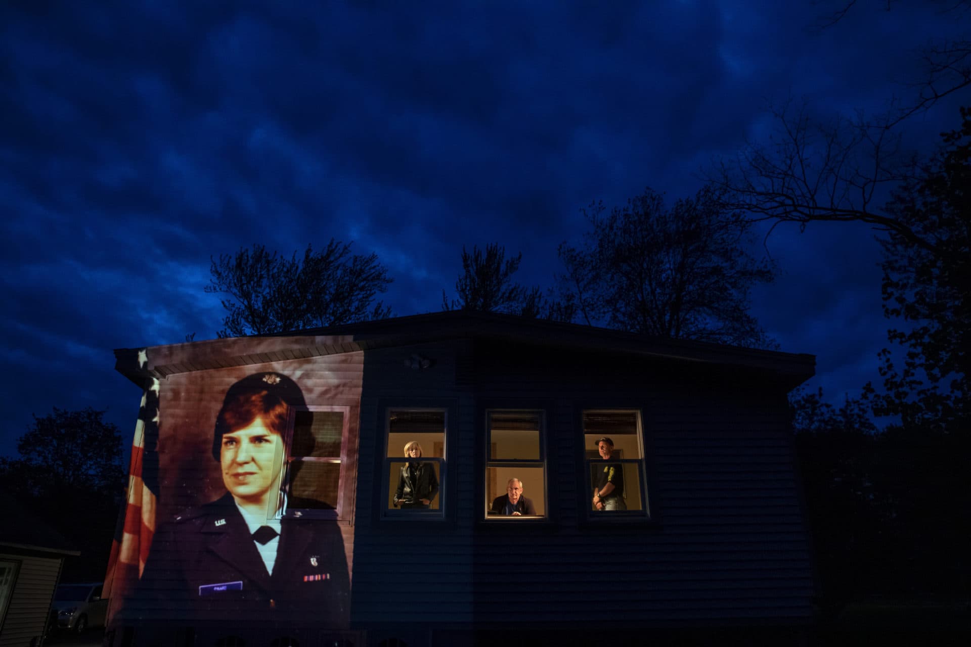 An image of veteran Constance &quot;Kandy&quot; Pinard is projected onto the home she grew up in with her sister, Tammy Petrowicz, left, and brothers, Paul, center, and Brian Driscoll in Florence, Mass. (David Goldman/AP)