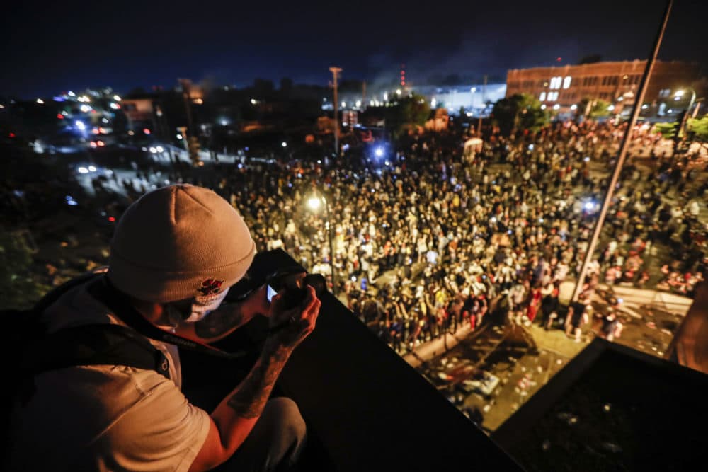 A protestor takes a picture of a demonstration from a roof in Minneapolis Thursday, May 28, 2020. Protests over the death of George Floyd, a black man who died in police custody Monday, broke out for a third straight night. (John Minchillo/AP)