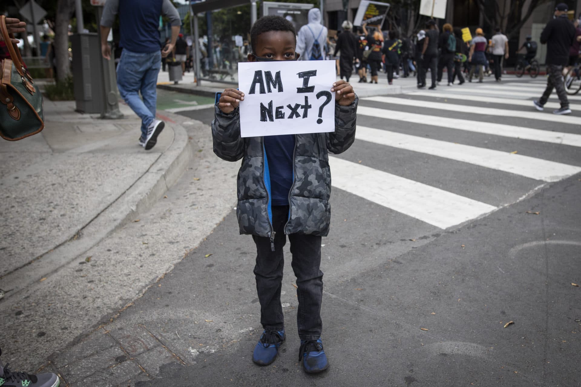 A boy holds a sign during a protest in downtown Los Angeles, Friday, May 29, 2020, over the death of George Floyd, who died in police custody on Memorial Day in Minneapolis. (AP Photo/Christian Monterrosa)