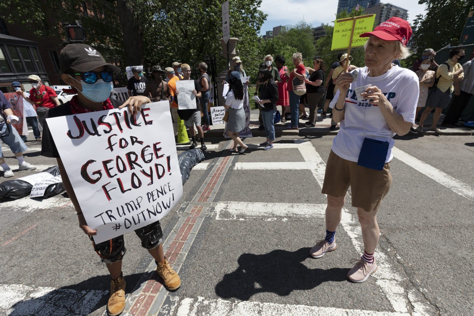A Trump supporter stands next to a woman protesting against the death in police custody of George Floyd, Saturday, May 30, 2020, in Boston. (AP Photo/Michael Dwyer)