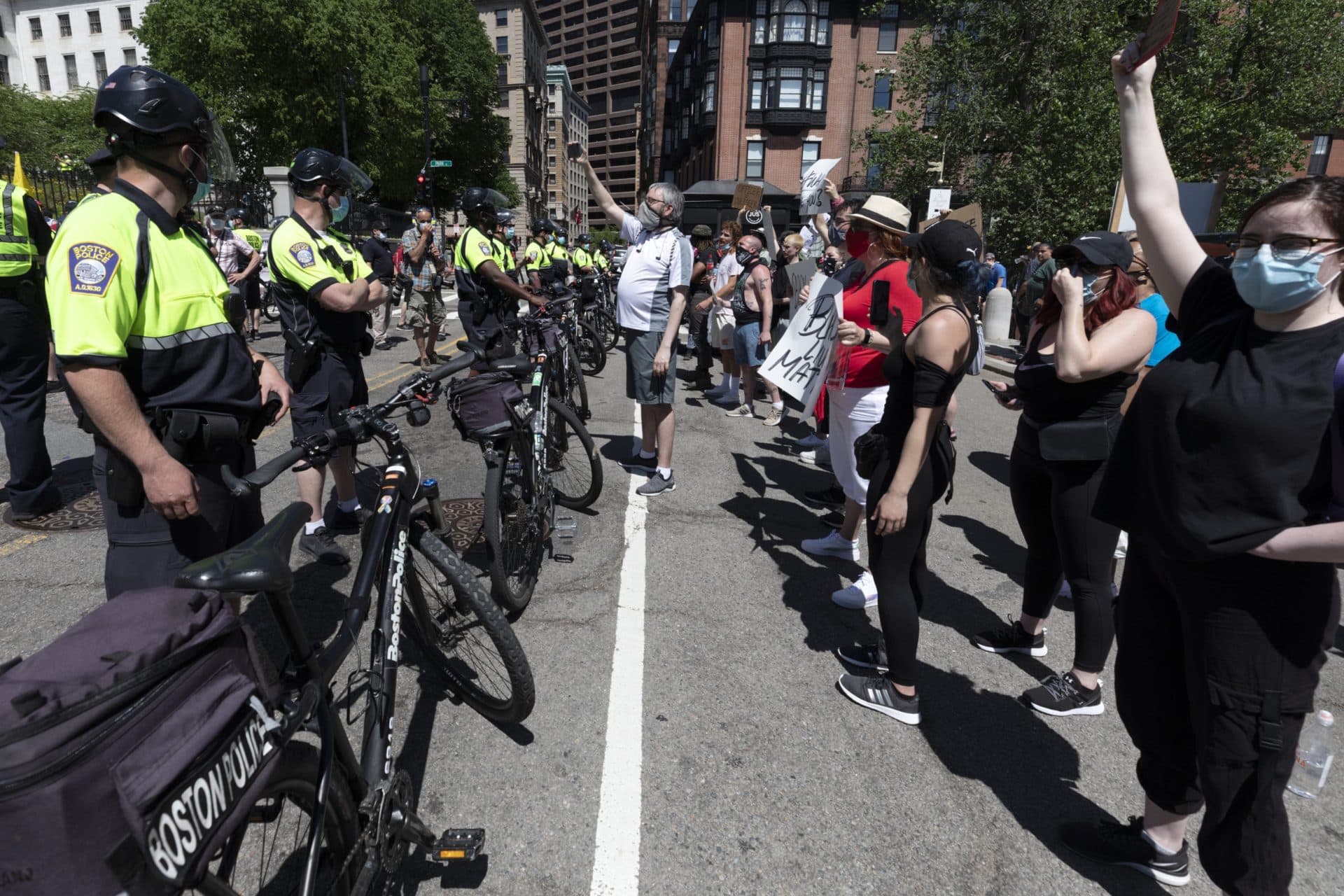 Police stand between counter-protesters and a demonstration calling for the lifting of all government restrictions relating to concern about the spread of COVID-19, Saturday, May 30, 2020, outside the Statehouse in Boston. (AP Photo/Michael Dwyer)