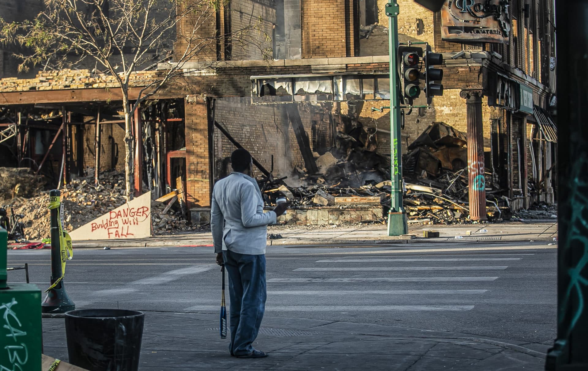 A man looks at the destruction aftermath of businesses along Lake Street, Sunday May 31, 2020, in Minneapolis. Outrage following the death of George Floyd, who died after being restrained by Minneapolis police officers on May 25, has led to the burning of businesses along the the Lake Street corridor where immigrants have found success. (AP Photo/Bebeto Matthews)