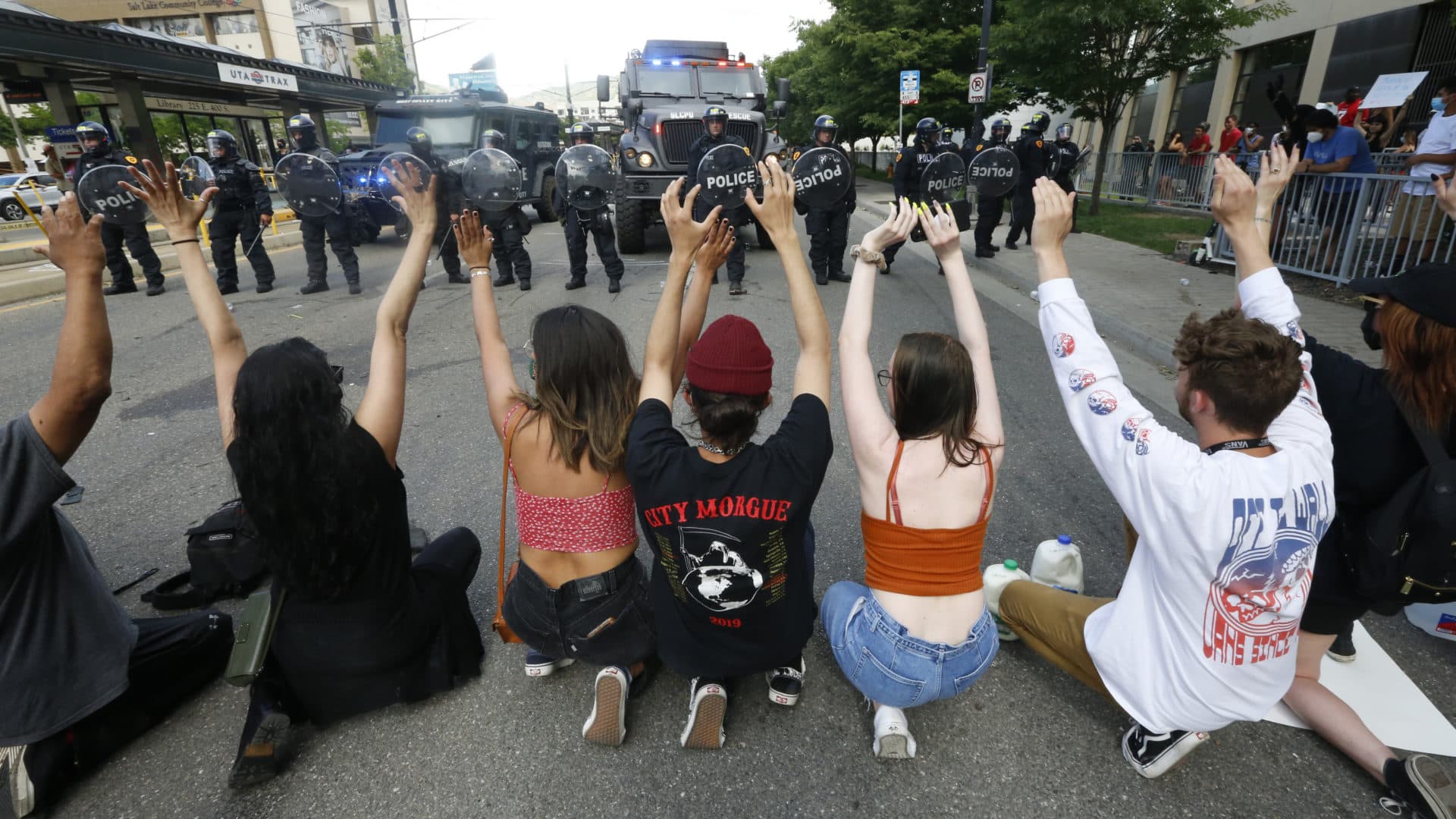 Protesters demonstrate in front of police Saturday, May 30, 2020, in Salt Lake City. Thousands of people converged on downtown Salt Lake City on Saturday to protest the death of George Floyd in Minneapolis, and some demonstrators set fire to a police car and threw eggs and wrote graffiti on a police station. (AP Photo/Rick Bowmer)