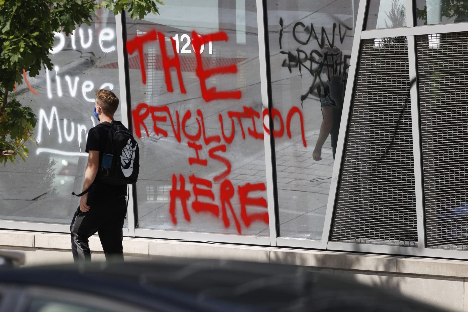 A pedestrian walks past graffiti sprayed on the windows of the ART Hotel in Denver on Sunday, May 31, 2020, during a protest over the death of Floyd, a black man who died after being restrained by Minneapolis police officers on May 25. (AP Photo/David Zalubowski)