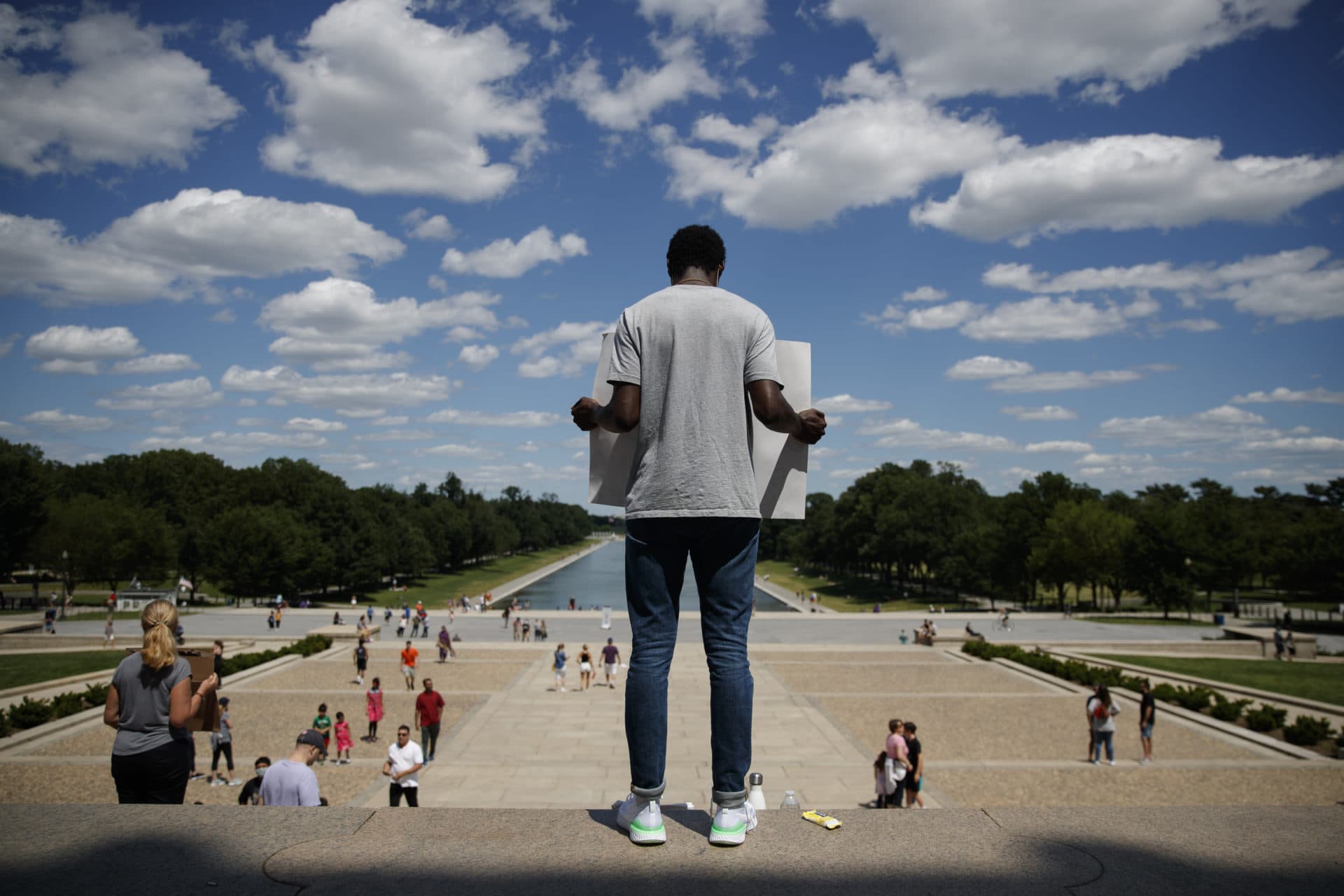 Yinka Onayemi holds a sign as he stands quietly on the steps of the Lincoln Memorial looking out over the National Mall in Washington, Sunday, May 31, 2020, to protest the death of George Floyd. Floyd died after being restrained by Minneapolis police officers. (AP Photo/Carolyn Kaster)