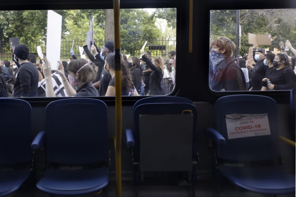 Protesters walk past an empty bus as they demonstrate Sunday, May 31, 2020, in Boston, over the death of George Floyd. (Steven Senne/AP Photo)