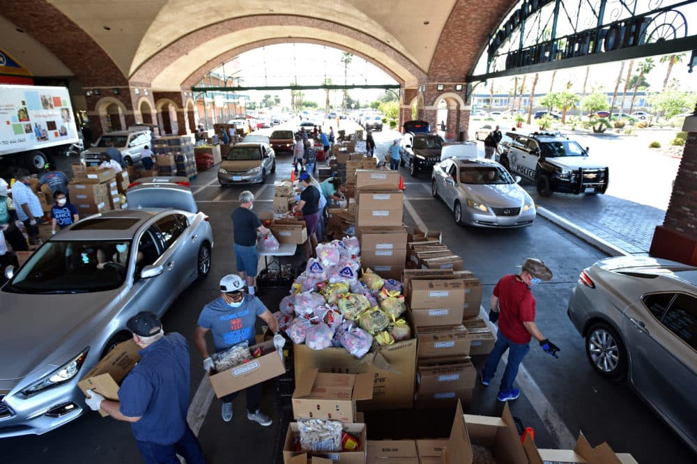 Volunteers give out groceries at a drive-thru Three Square Food Bank emergency food distribution site at Boulder Station Hotel & Casino in response to an increase in demand amid the coronavirus pandemic on April 29, 2020 in Las Vegas, Nevada. (DAVID BECKER/AFP via Getty Images)