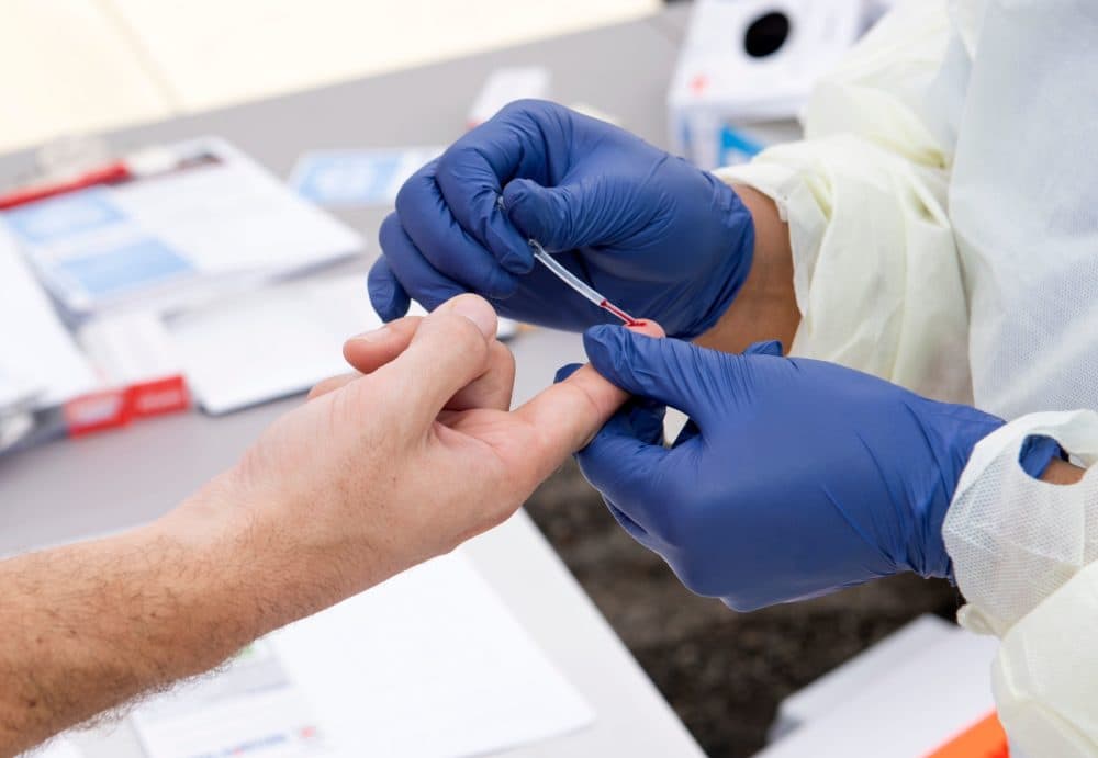 A health worker takes a drop of blood for the COVID-19 antibody test after at the Diagnostic and Wellness Center on May 5, 2020, in Torrance, California. (Valerie Macon/AFP/Getty Images)