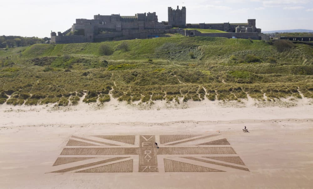 Andrew Heeley, 56, a maintenance manager at Bamburgh Castle, draws a giant Union flag on the beach beneath the castle in Northumberland, on the north east coast of England to mark the 75th anniversary of VE Day. (Owen Humphreys/PA Images via Getty Images)