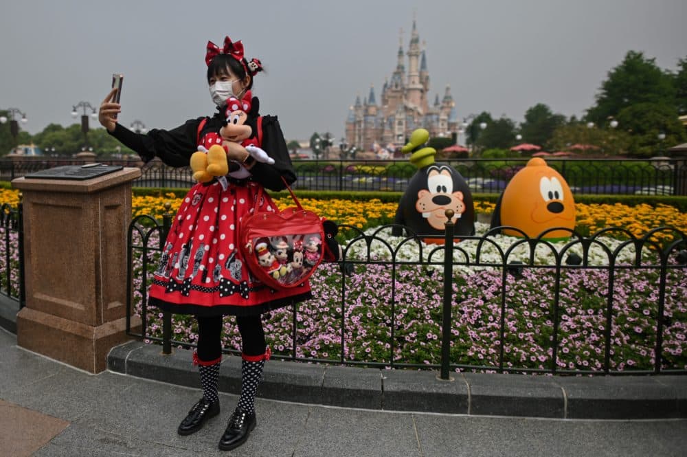 A woman wearing a face mask takes a selfie while visiting the Disneyland amusement park in Shanghai on May 11, 2020. (Hector Retamal/AFP via Getty Images)