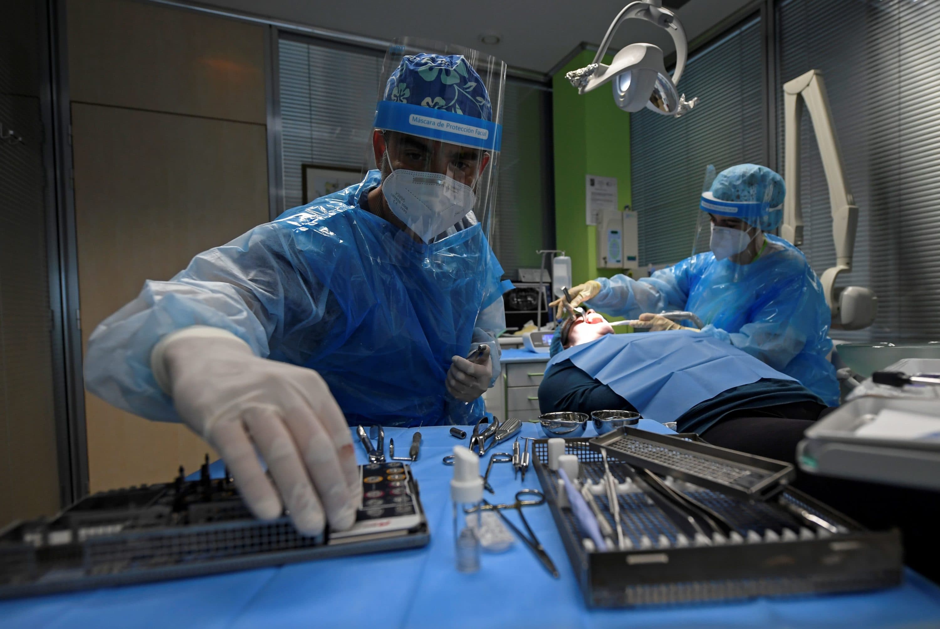 A dentist and clinical assistant perform a dental surgery on a patient at the Camarma Dental Clinic in Camarma de Esteruelas, near Madrid, on May 11, 2020. (Oscar Del Pozo/AFP via Getty Images)