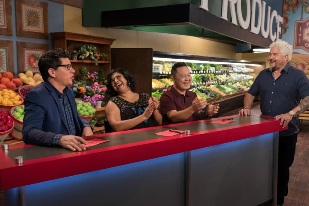 Judges Troy Johnson, Aarti Sequeira, and Jet Tila talk with Host Guy Fieri while the contestants prepare their dishes, as seen on Guy's Grocery Games, Season 14. (Courtesy, Food Network)