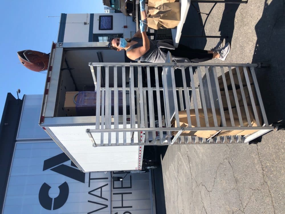 A volunteer from East Boston Social Centers helps with the food distribution. (Courtesy ICA)