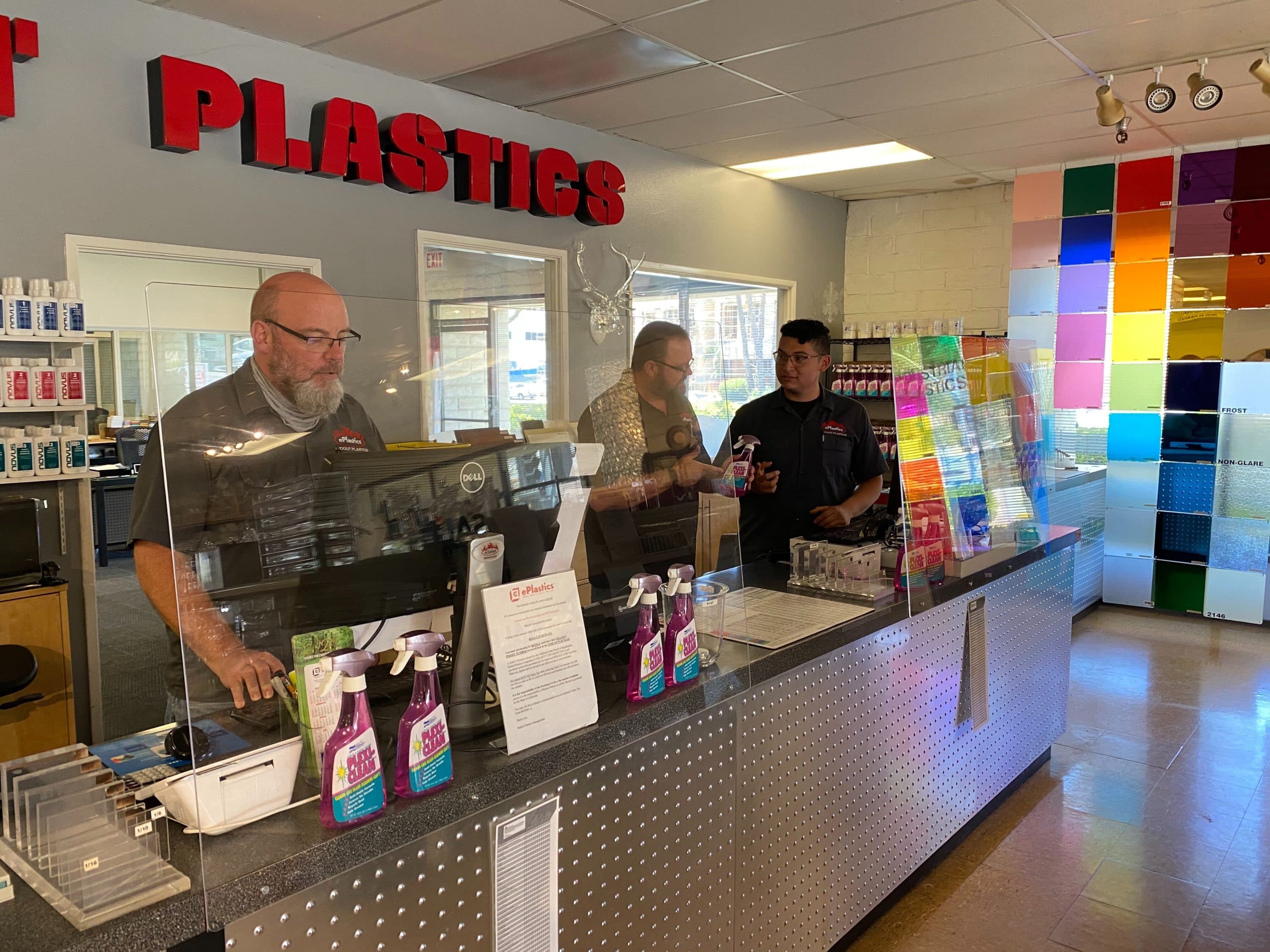 John Short (middle) of ePlastics in San Diego stands with employees behind their "sneeze guards." (Courtesy)