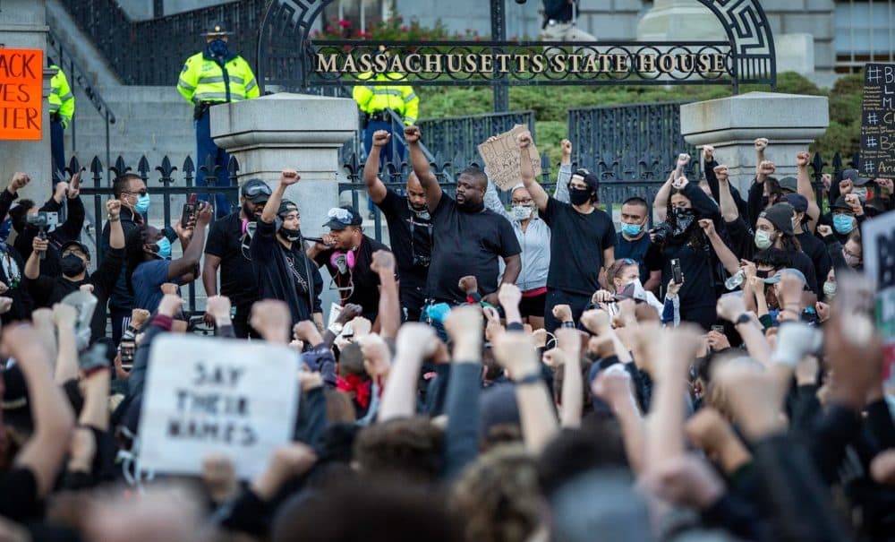 A protesters hold up their fists outside the State House. (Robin Lubbock/WBUR)