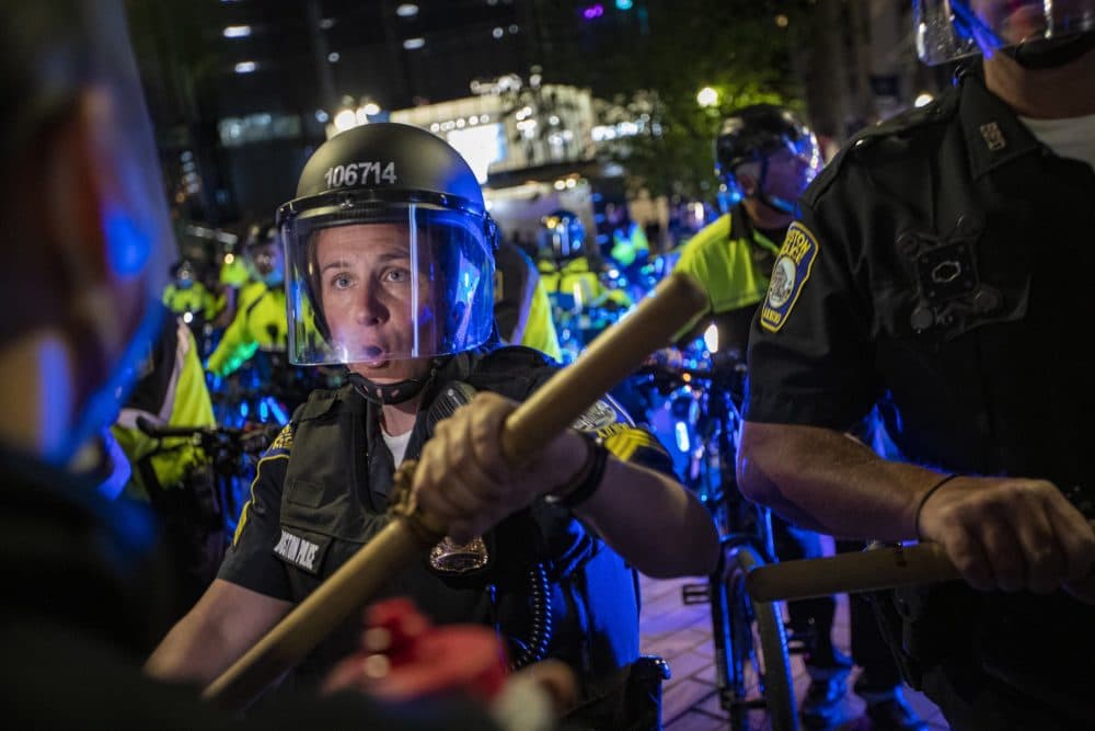 A line of Boston Police officers force protesters out of Downtown Crossing. (Jesse Costa/WBUR)