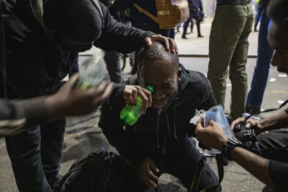 A protester has saline administered to him after he was pepper sprayed by Boston police on School Street. (Jesse Costa/WBUR)