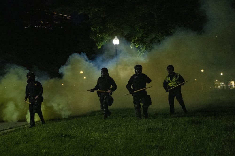Boston Police emerge from the cloud of tear gas in the Boston Common to clear out protesters. (Jesse Costa/WBUR)