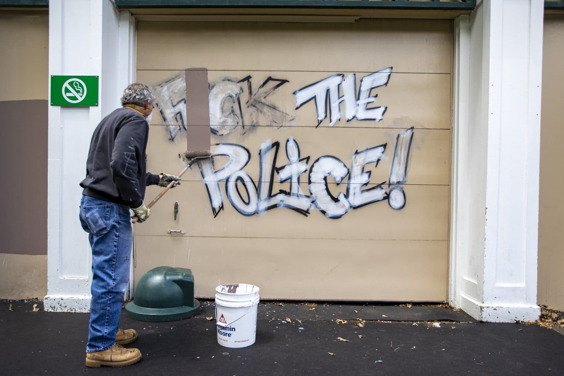 A Boston Parks and Recreaton worker paints over graffiti on a wall of the Frog Pond Pavilion in the Boston Common, left by protesters after the Black Lives Matter rally at the Massachusetts State House. (Jesse Costa/WBUR)