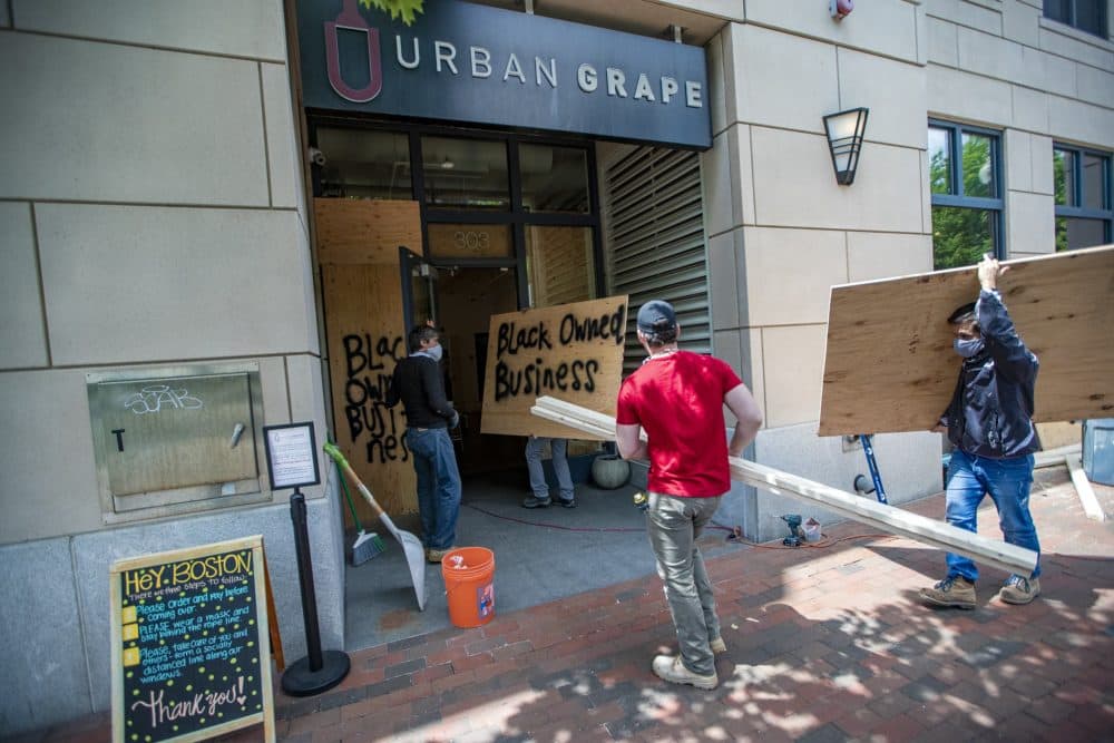 Contractors bring plywood painted with the words ”Black Owned Business” into The Urban Grape, to be place into the windows. During the night of the Black Lives Matter rally, one window was broken in an act of vandalism. (Jesse Costa/WBUR)