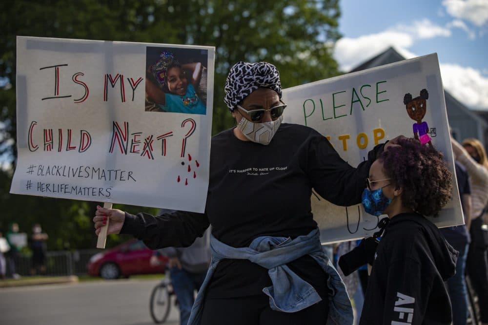 A woman and her daughter attended a anti-police brutality vigil at the rotary by the Holy Name Parish in West Roxbury on Monday night. (Jesse Costa/WBUR)