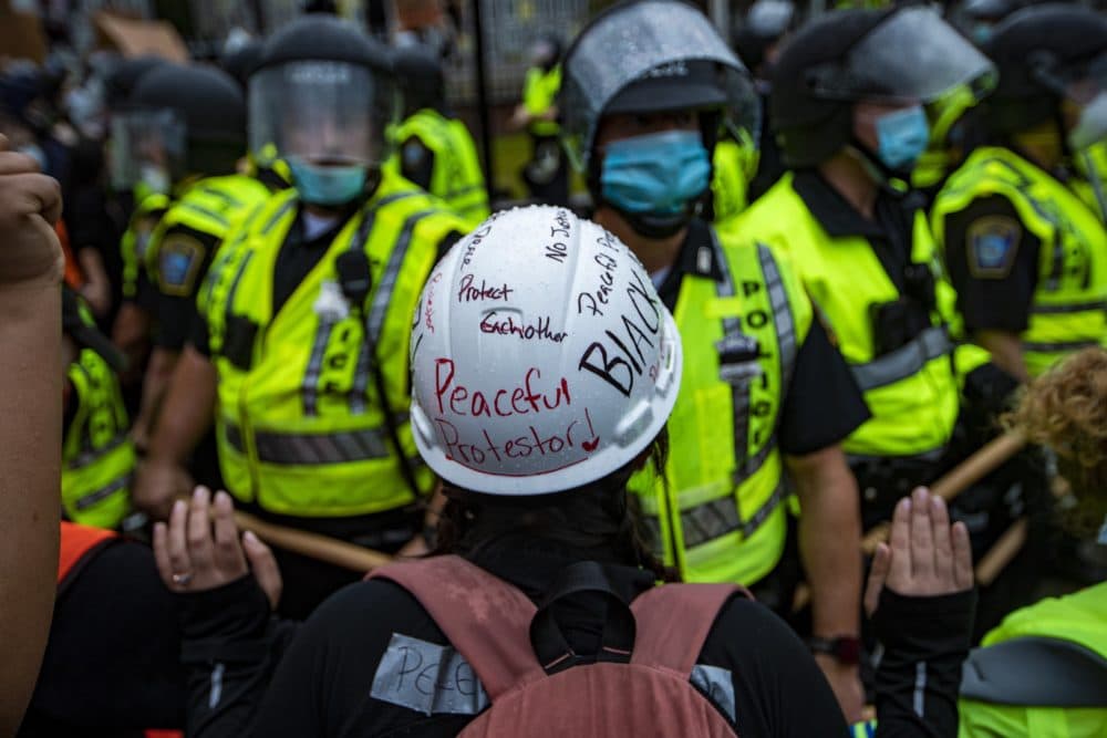 A protester confronts Boston Police with hands in the air in front of Forest Hills Station in Jamaica Plain. (Jesse Costa/WBUR)