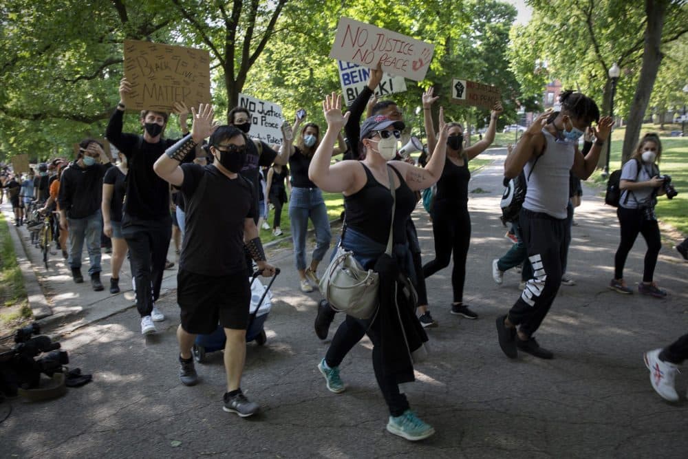 Protesters raise their hands as they march around Boston Common. (Robin Lubbock/WBUR)