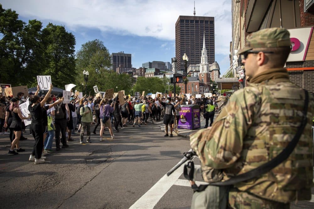 Police and National Guard soldiers watch as demonstrators march down Tremont Street. (Robin Lubbock/WBUR)