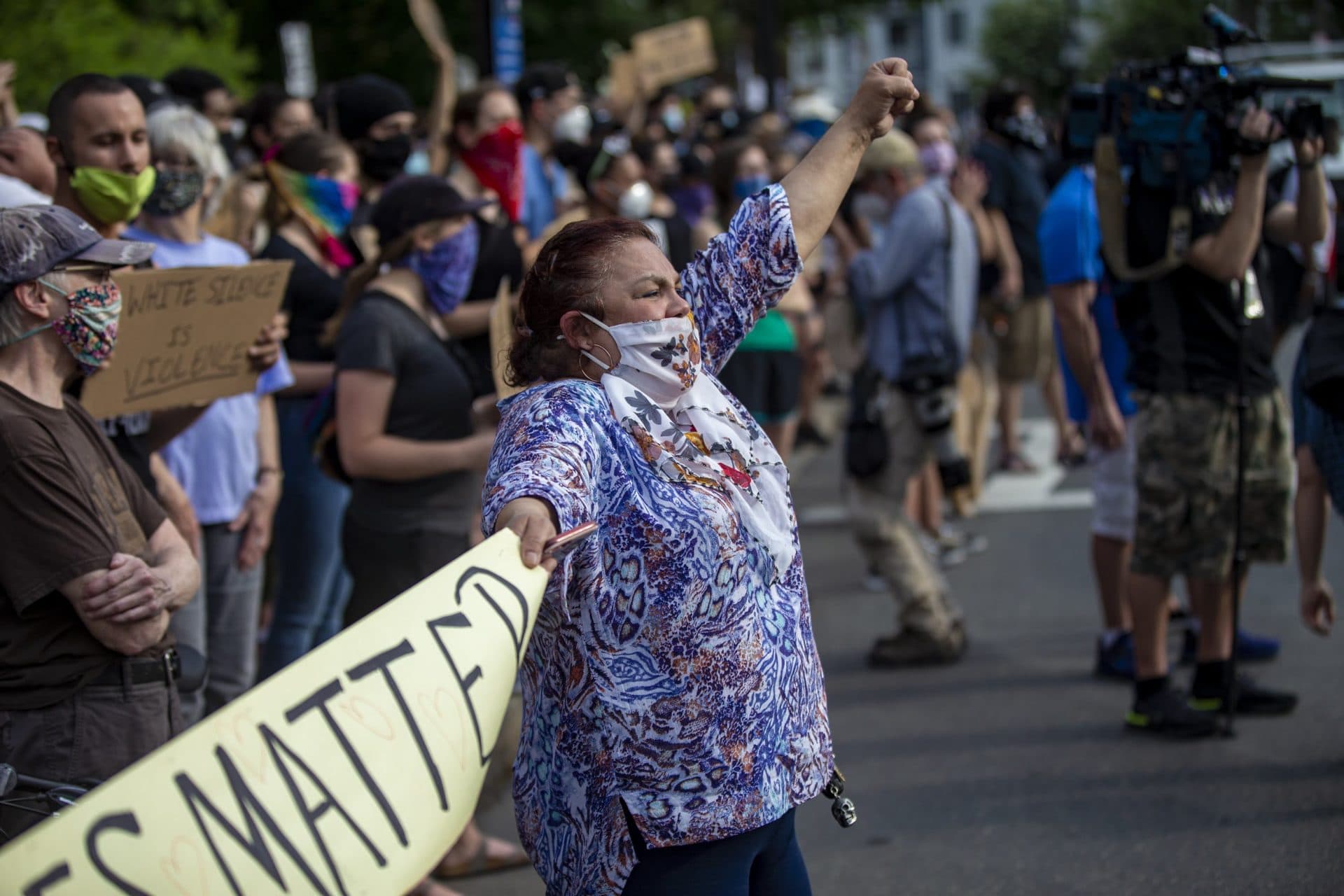 Evelyn Gallego throws her fist and chants with hundreds of other protesters gathered at the Soldier’s Memorial in Jamaica Plain. (Jesse Costa/WBUR)