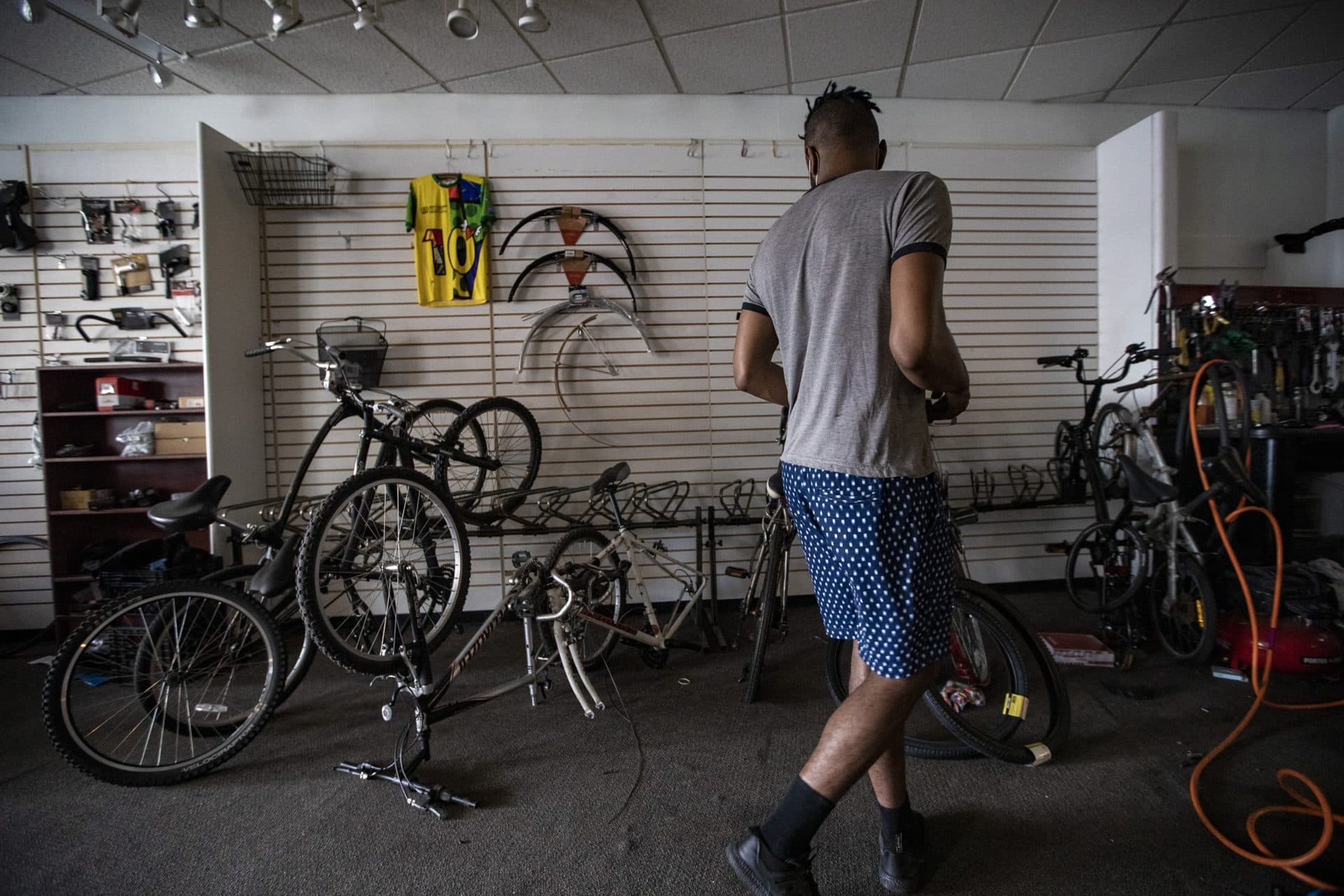 Noah Hicks walks past a group of bicycles that had parts removed by looters. (Jesse Costa/WBUR)