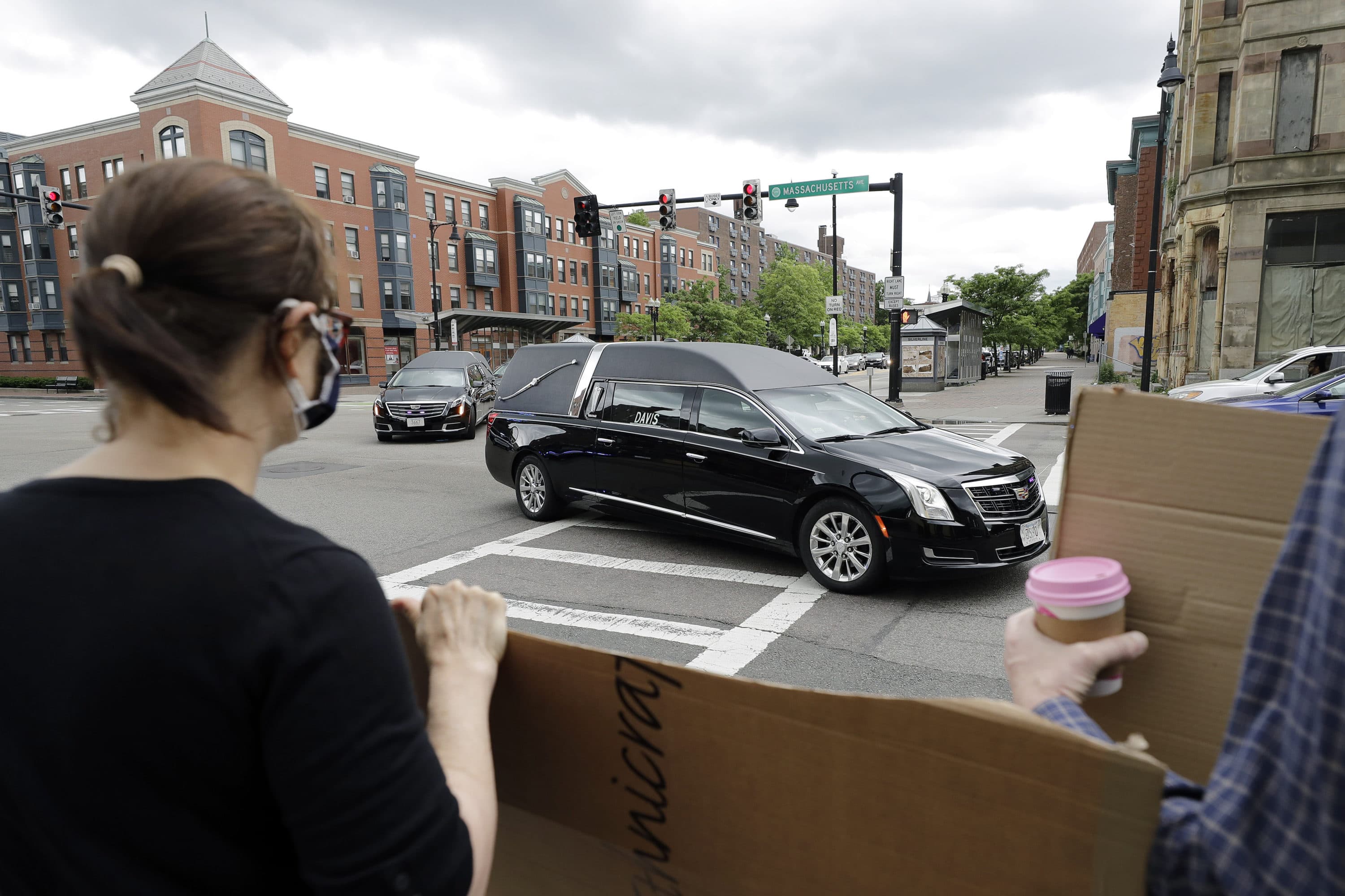 People display placards Sunday while watching a procession of vehicles, including three hearses meant to honor fallen George Floyd, Breonna Taylor and Ahmaud Arbery, as it makes its way through Boston. (Steven Senne/AP)