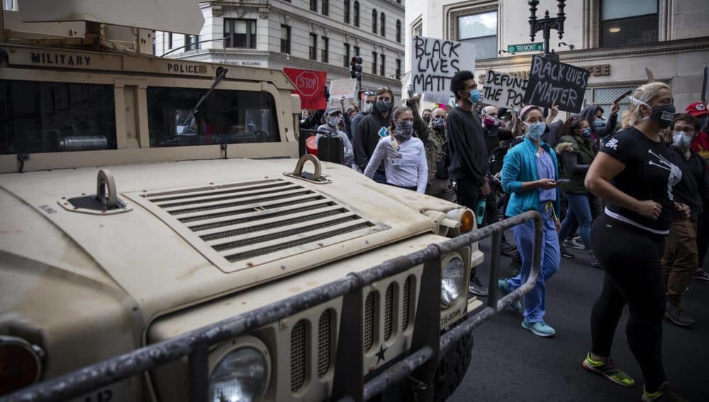 Black Lives Matter protesters walk by a military police vehicle on Tremont Street. (Robin Lubbock/WBUR)