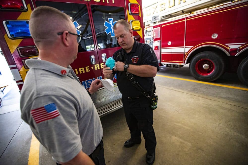 Duxbury Fire Chief Joe Reardon hands N95 masks to paramedic Justin Stratton after he returns from a call. (Jesse Costa/WBUR)