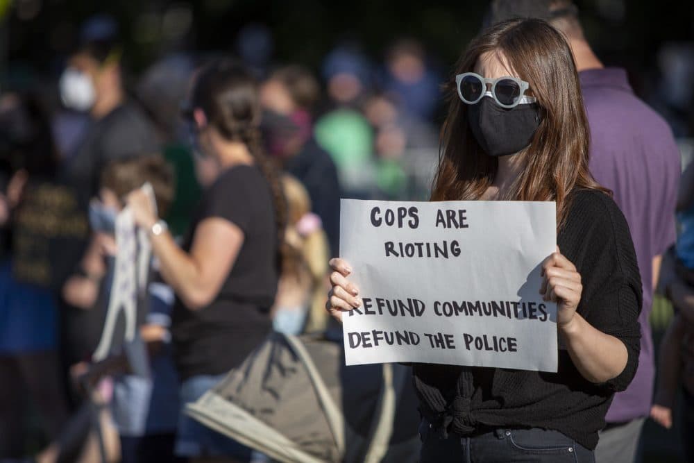 A protester in West Roxbury urges refunding communities and defunding the police. (Robin Lubbock/WBUR)