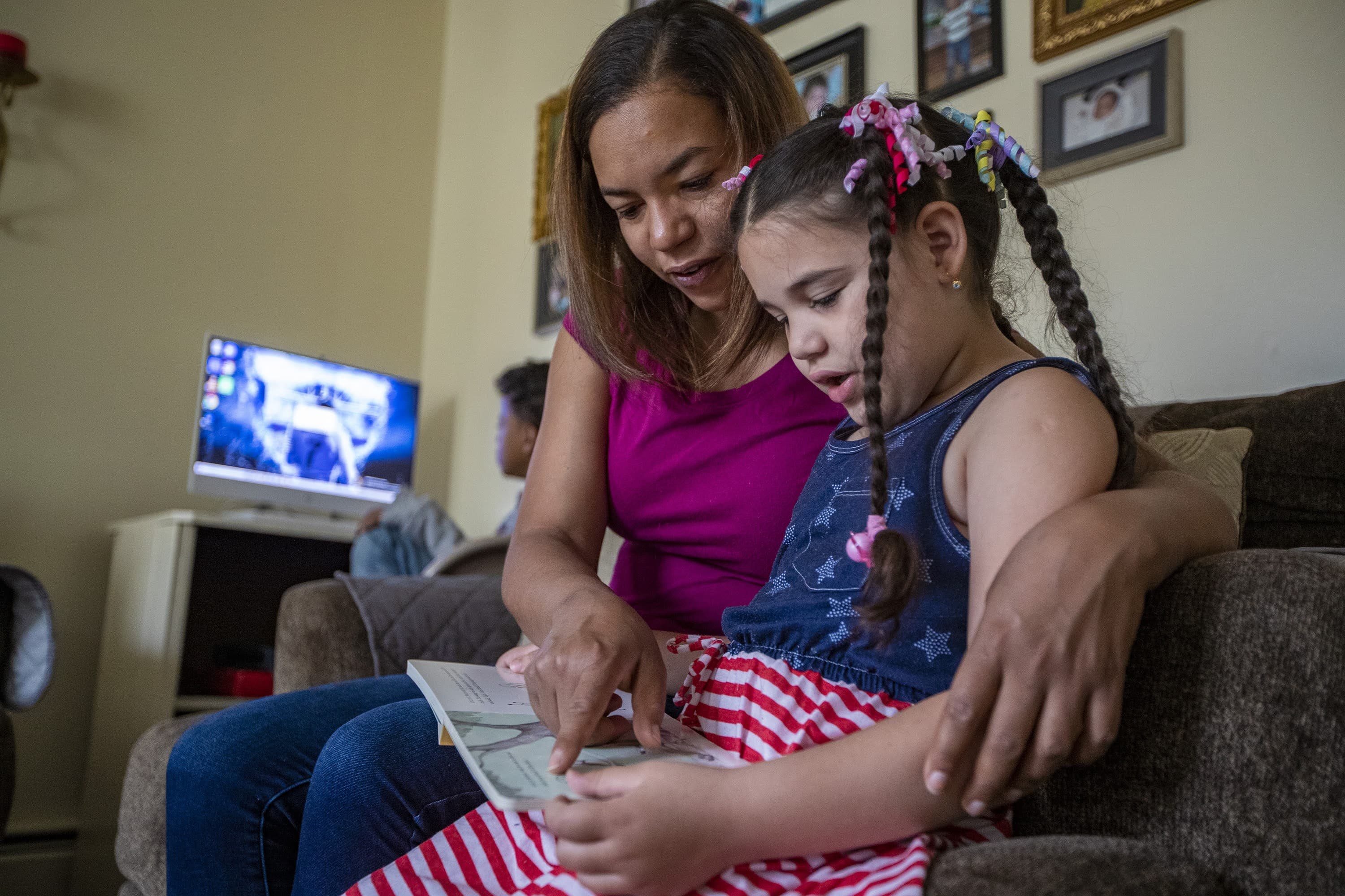 Margareth Jesus y su hija Lucero leen juntas mientras Jesus espera a que comience su clase online. (Jesse Costa/WBUR)