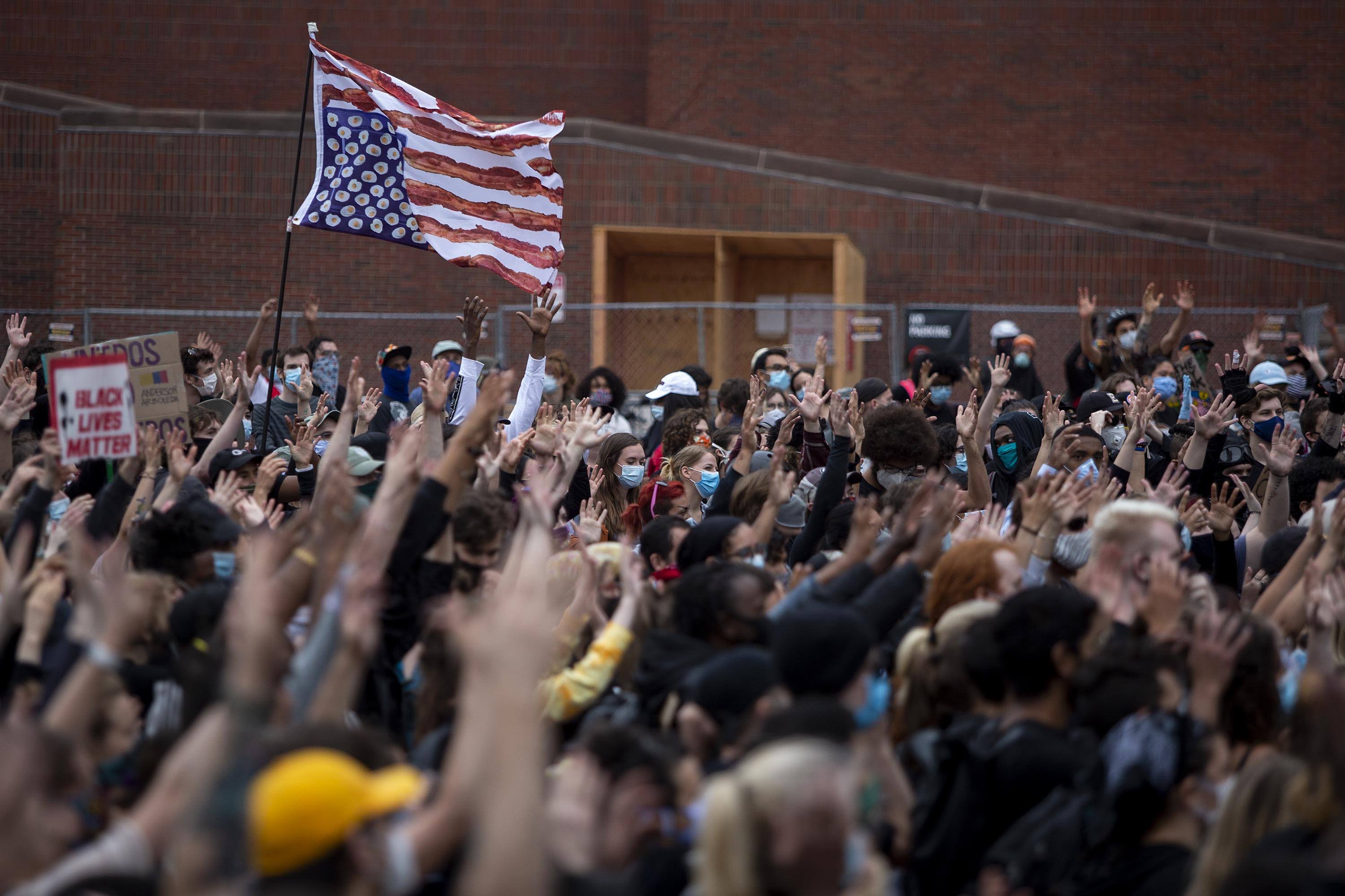 Protesters at the For The People march raise their hands in unison in City Hall Plaza. (Robin Lubbock/WBUR)