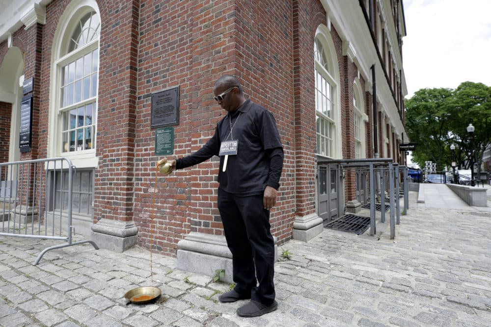 Kevin Peterson, founder and executive director of The New Democracy Coalition pours a red substance as a protest meant to symbolize the blood of fallen black people who died under under white suppression and slavery. (Steven Senne/AP)