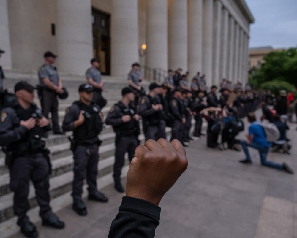 Protesters kneel and raise their arms if front of a row of police officers as they gather peacefully to protest the death of George Floyd at the State Capital building in downtown Columbus, Ohio, on June 1, 2020. (Seth Herald/AFP/Getty Images)