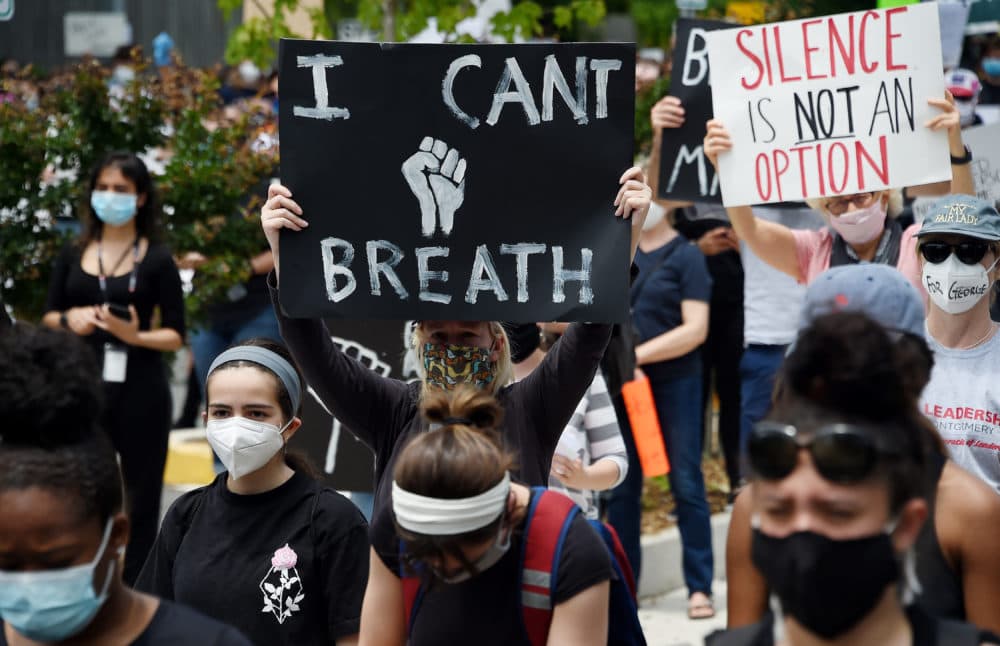 Peaceful demonstrators hold signs as they protest the death of George Floyd outside the Bethesda Library on June 2, 2020 in  Bethesda, Maryland. (Olivier Douliery/AFP via Getty Images)